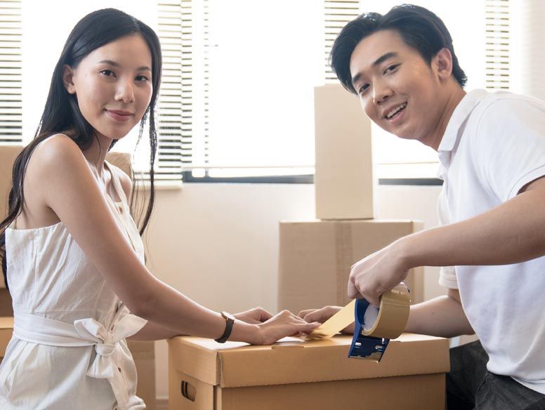 Asian couple packing moving boxes