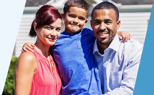 Family of 3 smiling in front of a house.
